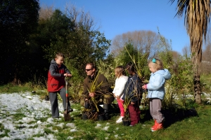 A park ranger is talking to a group of children in a bush