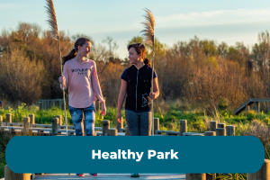 Two girls walk along a boardwalk with the copy Healthy Park Award