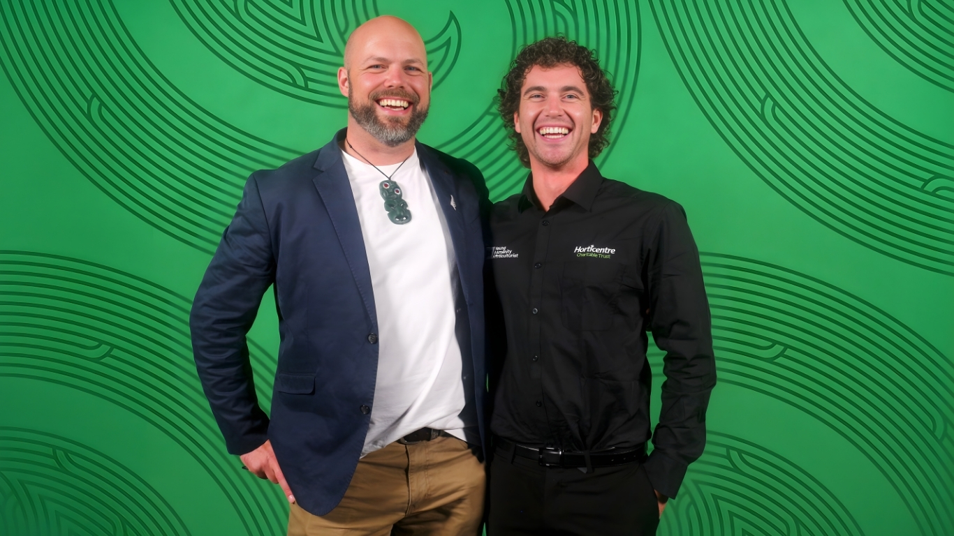 Two men stand for a photo, one is holding an award