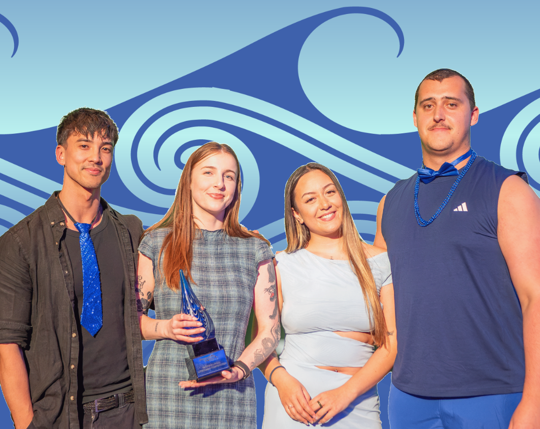 Four young adults posing together against a blue background while one holds an award they won as a team.