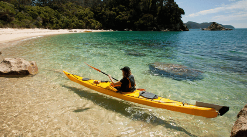 A person kayaks onto a beach