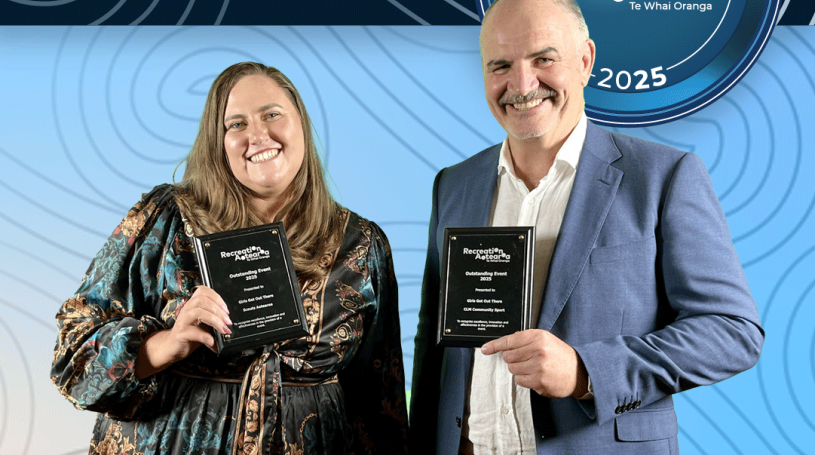 A man and woman standing together holding award plaques and smiling. The background is a blue koru pattern with text at the top and bottom of the image. The top text says "2025 Recreation Awards Winner," and the bottom says "Outstanding Event: Girl Get Out There"