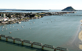 An image of Tauranga from the sky with a bridge in the foreground and Mauao in the background