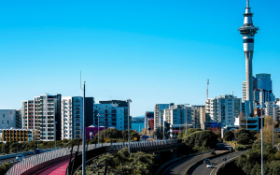 An image of Auckland with a motorway in the foreground and the Sky Tower in the background