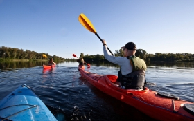 A group of three people kayak down a river