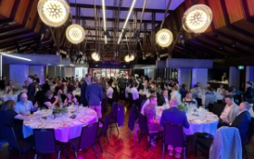 A group of people sit in a room having dinner
