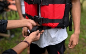 A child is wearing a lifejacket - an adult is buckling it up for them