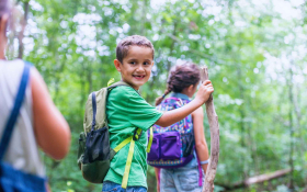 Children hike along a trail, one turns back and smiles at camera
